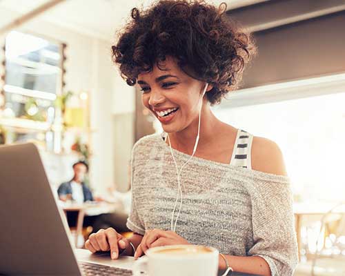 photo of a woman using a laptop with headphones