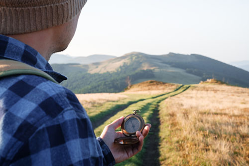 Man with compass in hand on mountains road.